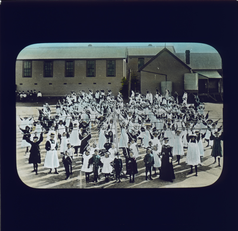 School students lined up as if performing, with long poles and a May Pole [Hawkesbury Agricultural College (HAC)]