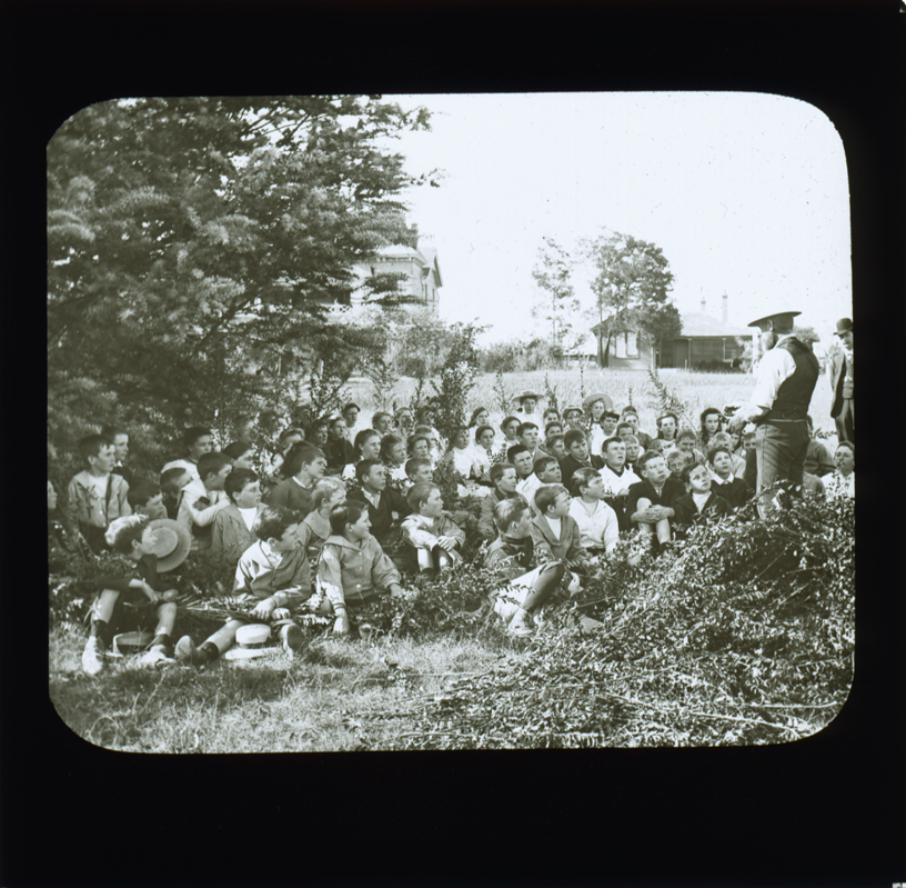 Group of school students sitting under a tree listening to a teacher [Hawkesbury Agricultural College (HAC)]