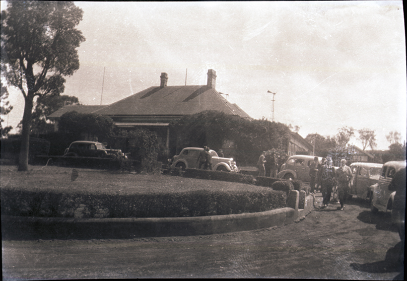 House with circular drive and cars pulled up out the front (unidentified)