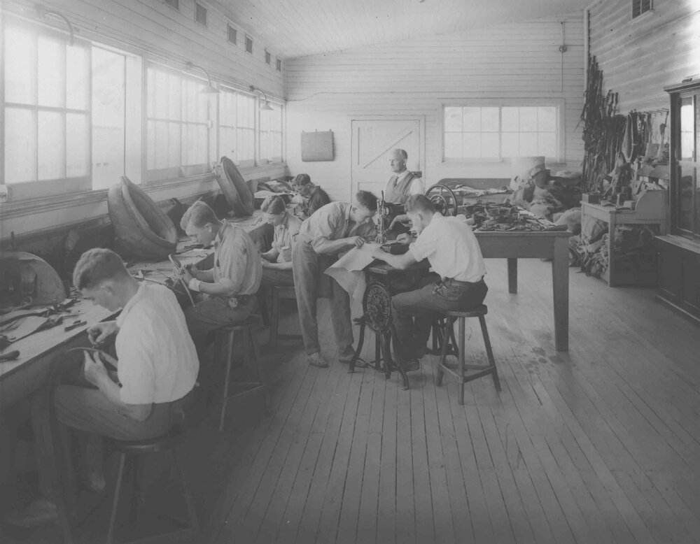 Saddlery Shop (interior) - Students seated at benches and two working a sewing machine [Hawkesbury Agricultural College (HAC)]