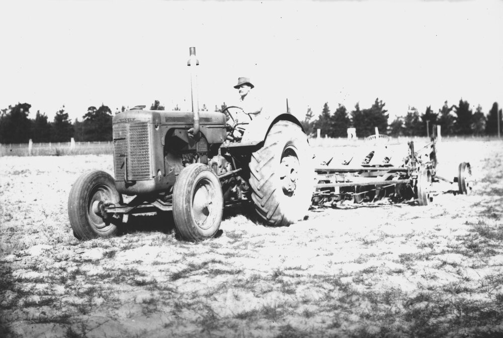 A man working on a tractor, with a ploughing attachment [Hawkesbury Agricultural College (HAC)]