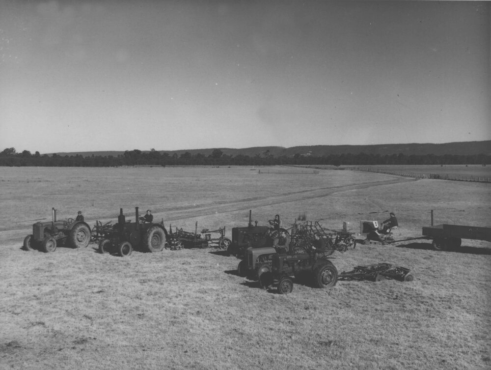 Tractors assembled in display in a paddock with horse teams in the background [Hawkesbury Agricultural College (HAC)]