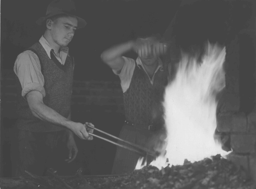 Blacksmith Shop (interior) - Two students working at the forge, heating a horse shoe [Hawkesbury Agricultural College (HAC)]