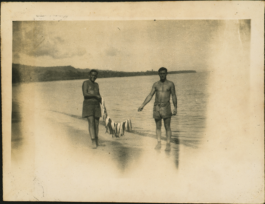 Two men holding a haul of sea mullet strung on a line between them