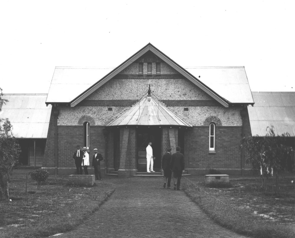 Quadrangle - Men standing outside the Dining Hall - the paths have been made and trees planted [Hawkesbury Agricultural College (HAC)]