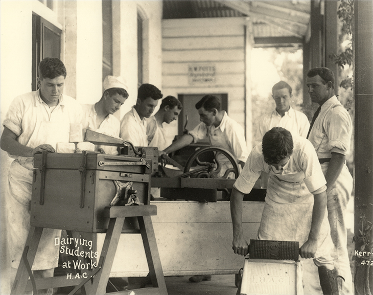 Dairy Factory (exterior): A posed photo of dairy students making butter under supervision on verandah of dairy factory (Print 2 of 2) - Cropped [Hawkesbury Agricultural College (HAC)]
