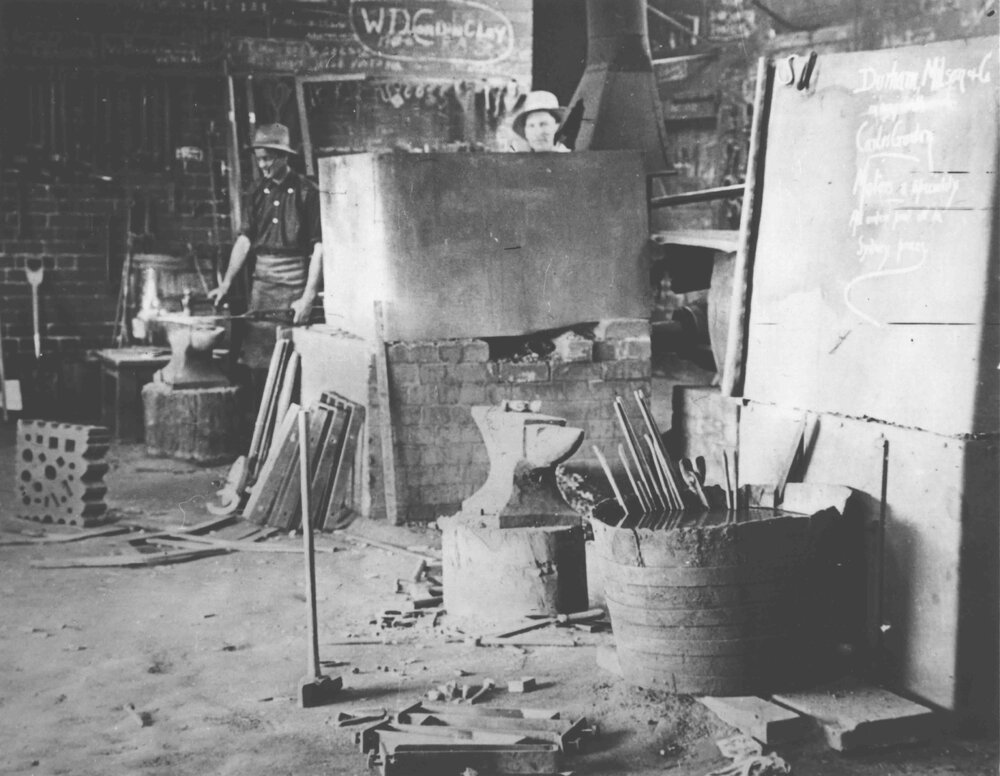 Blacksmith Shop (interior) - Two men at work [Hawkesbury Agricultural College (HAC)]