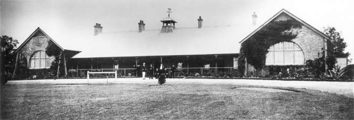 Main Administration Building - The first College building, with seven men (formally dressed) standing at the front entrance [Hawkesbury Agricultural College (HAC)]