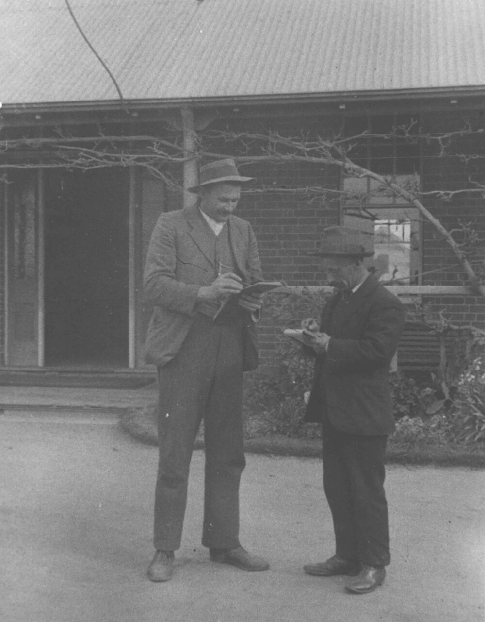Winter School for Farmers, 1910 - Two student farmers standing in front of the Main Administration Building writing in note books [Hawkesbury Agricultural College (HAC)]