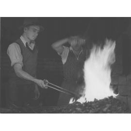 Blacksmith Shop (interior) - Two students working at the forge, heating a horse shoe [Hawkesbury Agricultural College (HAC)]