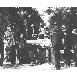 Student holding an ostrich by its neck, another holding a plume while others look on [Hawkesbury Agricultural College (HAC)]