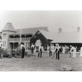 Students scything front lawn under instruction [Hawkesbury Agricultural College (HAC)] - Print 1 of 2 - Uncropped