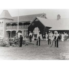 Students scything front lawn under instruction [Hawkesbury Agricultural College (HAC)] - Print 2 of 2 - Cropped