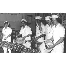 Cannery: Students standing in front of a conveyor belt(?) holding large containers of peas [Hawkesbury Agricultural College (HAC)]