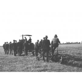 Tractor drawing a plough - A group of farmers watching and walking alongside the demonstration [Hawkesbury Agricultural College (HAC)]