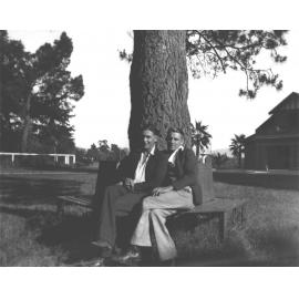 Memorial Hall - Two students seated on a bench under a pine tree [Hawkesbury Agricultural College (HAC)]