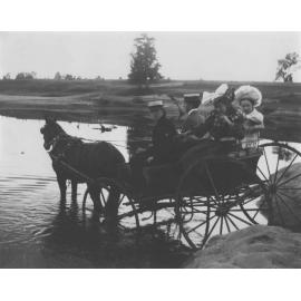 Two students in a horse and buggy in water (dam or river?) with two young ladies in the back [Hawkesbury Agricultural College (HAC)]