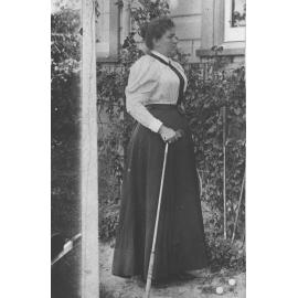 Portrait: Mrs JJ McCue - standing outside a residence holding a golf iron with two golf balls at her feet [Hawkesbury Agricultural College (HAC)]
