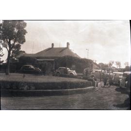 House with circular drive and cars pulled up out the front (unidentified)